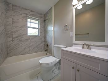 A white bathroom with a marble tiled shower.